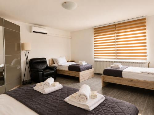 a hotel room with two beds and a chair at Central No1-Apartments in Golubac