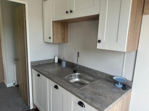 a kitchen with a sink and white cabinets at Atlantic Breeze, Mullacott Park in West Down