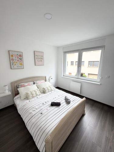 a white bedroom with a large bed with a large window at Au fil de la Blies in Bliesbruck