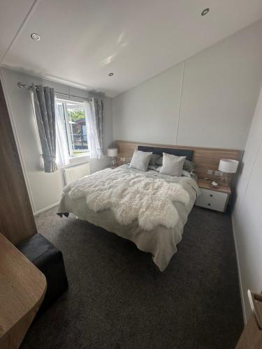 a bedroom with a large bed and a window at Atlantic Breeze, Mullacott Park in West Down