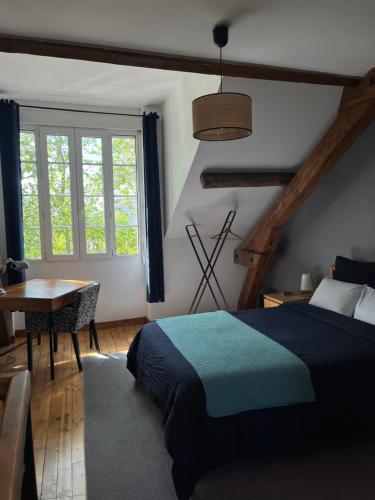a bedroom with a bed and a table and window at Duplex de charme en centre ville avec terrasse in Brive-la-Gaillarde