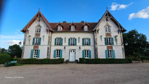 a large white house with green windows and a sky at Chambre Napoléon III in Fleuriel