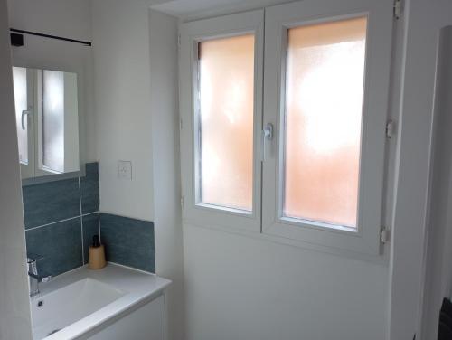 a bathroom with a sink and two windows at Gite La maison du gardien in Marcillac-Vallon