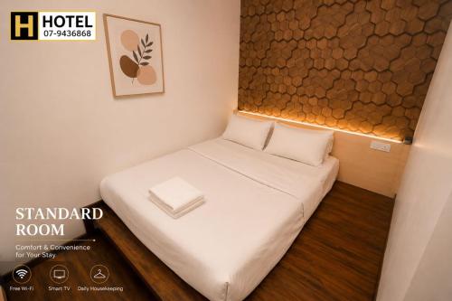 a small room with a small bed with white sheets at H Hotel in Segamat