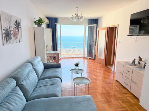 a living room with a blue couch and a view of the ocean at Sea Time Apartment in Budva