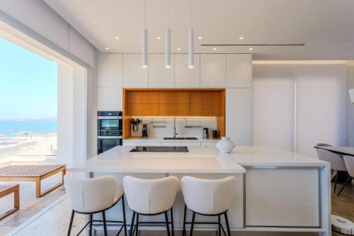 a kitchen with a large white island with bar stools at Olymp Luxury Residence in Kissonerga