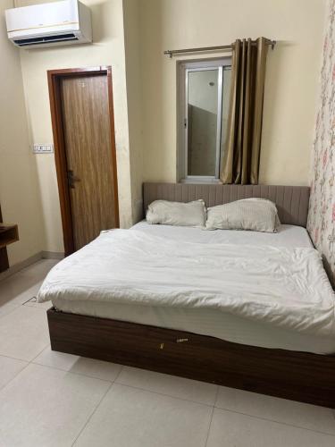 a bed with white sheets and a window in a room at KK Hotel in Jaipur