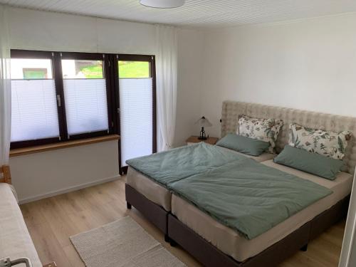 a bedroom with a large bed and two windows at Fewo Fernblick in Much
