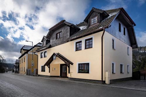 an old white building with a black roof at Avama - apartmány Srní in Srní