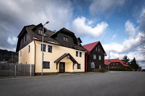 a white and black house on the side of a street at Avama - apartmány Srní in Srní