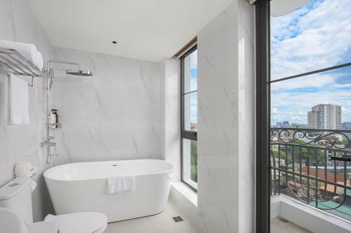 a white bathroom with a tub and a window at A25 - Premium Hotel - 95 Lò Đúc in Hanoi