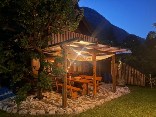 a wooden table under an umbrella on a stone patio at Edi Cottage in Bovec
