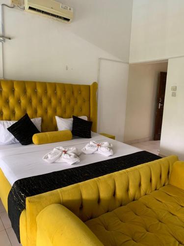 a large bed with a yellow headboard and a yellow couch at MJ Marina in Mtwapa
