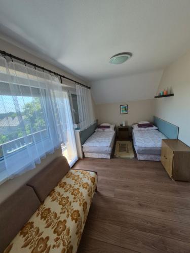 a room with two beds and a couch and a window at Ország Apartmanház in Zalakaros
