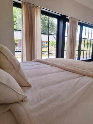 a white bed with pillows in a bedroom with windows at Villa Hartebos in Kaprijke