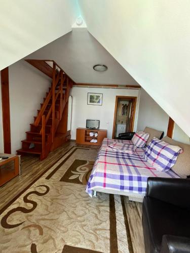 a attic room with a bed and a staircase at Casa cu Stuf Olimp in Olimp