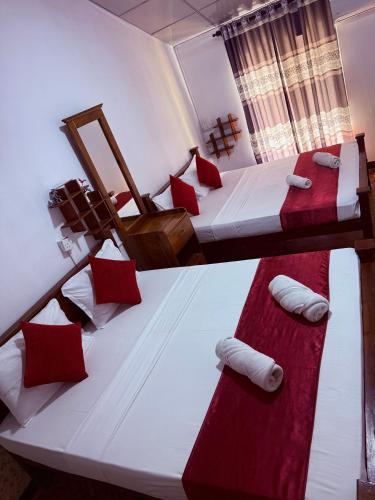 two beds in a room with red and white at Lake Classical Guest House in Kandy