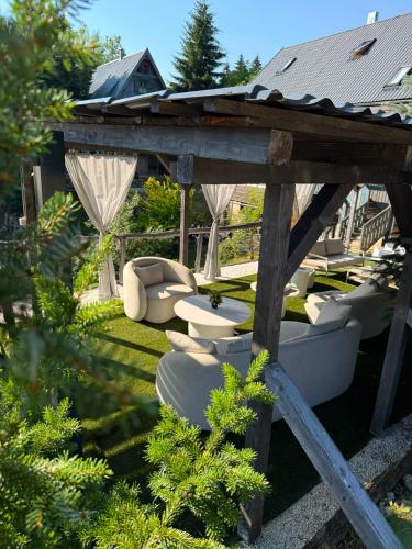 a wooden gazebo with chairs and tables in a yard at Plitvice Lakes Hotel Ethno Houses in Plitvička Jezera
