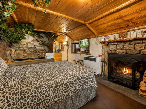 a bedroom with a bed and a stone fireplace at Castle Wood Cottages in Big Bear Lake