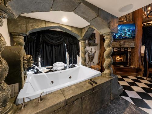 a bath tub in a stone room with a fireplace at Castle Wood Cottages in Big Bear Lake