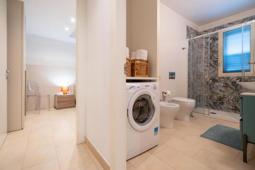 a white washing machine in a bathroom with a toilet at LOGGIATO HOUSE-Ispica in Ispica
