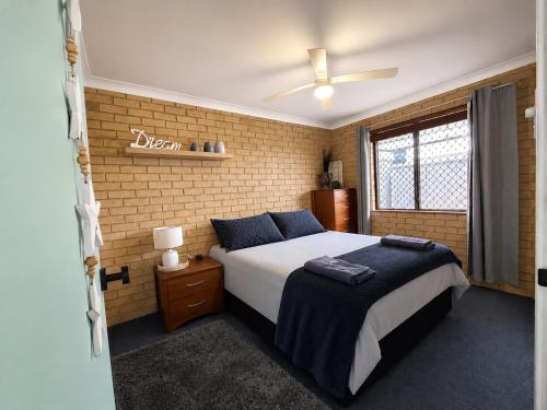 a bedroom with a bed and a brick wall at Champion Bay Coastal Stay in Geraldton