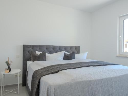 a bedroom with a large bed with a gray headboard at Apartment Rahat in Ližnjan