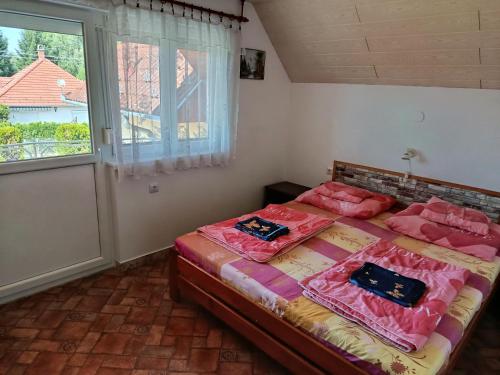 a bedroom with a bed with pink sheets and a window at Árvácska Nyaraló in Balatonmáriafürdő