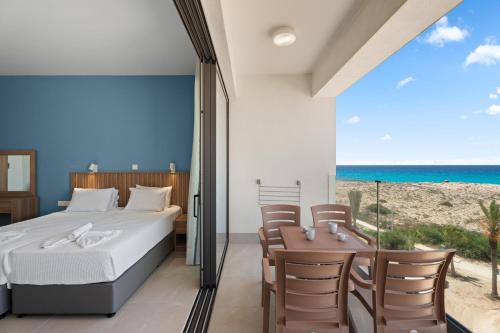 a bedroom with a bed and a view of the beach at Kritamo Suites Sandy Bay in Ayia Napa