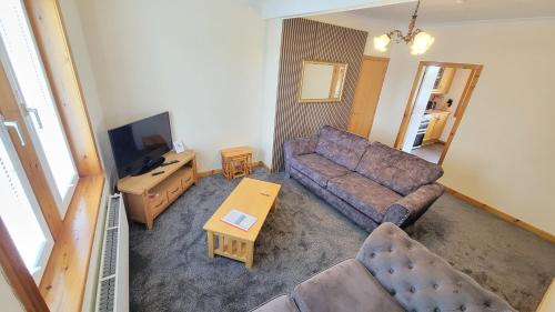 a living room with a couch and a tv at Stornoway Stays Apartment in Stornoway