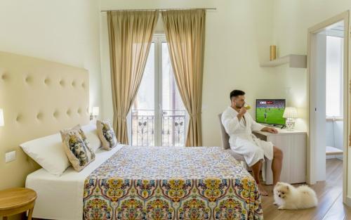 a man sitting at a desk in a hotel room at Kèramos Luxury Rooms in Sciacca