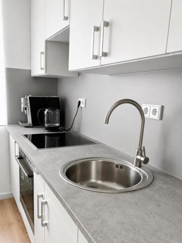 eine Küche mit Edelstahlspüle und Mikrowelle in der Unterkunft NOVA Living, Balkon, Nähe Altstadt & kostenlose Tiefgarage in Würzburg