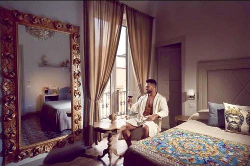 a man sitting in front of a mirror in a bedroom at Kèramos Luxury Rooms in Sciacca