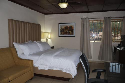 a bedroom with a bed and a desk and a window at The Stafford Lodge in Freetown