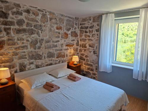 a bedroom with a bed and a stone wall at House Antica in Lastovo