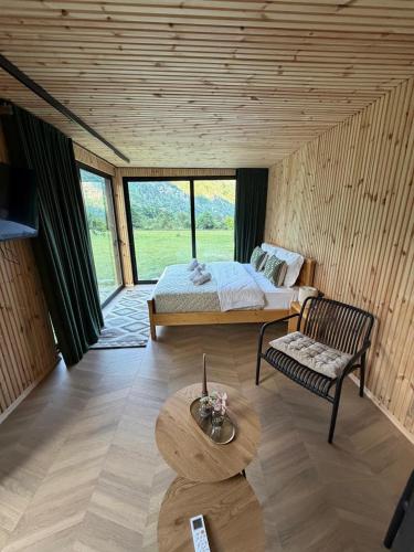 a bedroom with a bed and a chair and a table at Villa Ujëvara e vogël in Theth