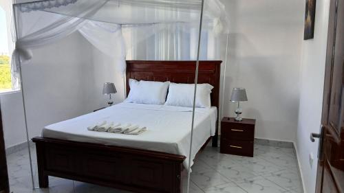 a bedroom with a canopy bed with white sheets and pillows at Hermit Homes in Mombasa