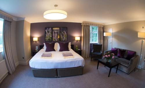 a hotel room with a large bed and a couch at Hogarths Stone Manor in Kidderminster