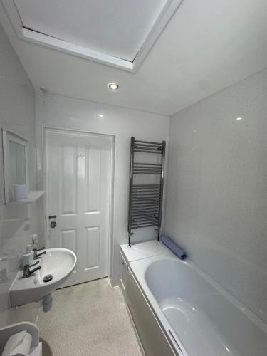 a white bathroom with a tub and a sink at Little Newlyn in Newlyn