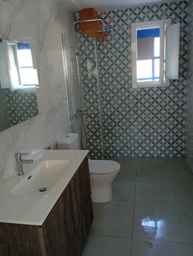 a bathroom with a sink and a toilet and a window at Central Apartments in Lefkos Karpathou