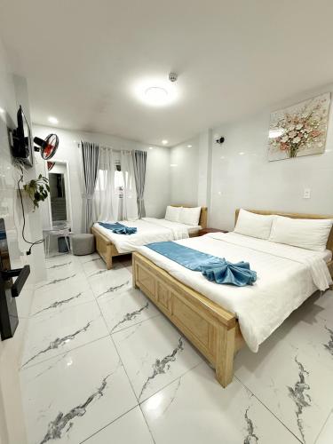 two beds in a room with white marble floors at Hoang Vu Guest House in Da Lat