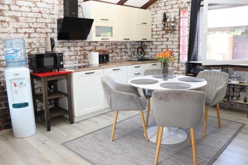 a kitchen with white cabinets and a table and chairs at Kuća za odmor Leon in Vinkovci