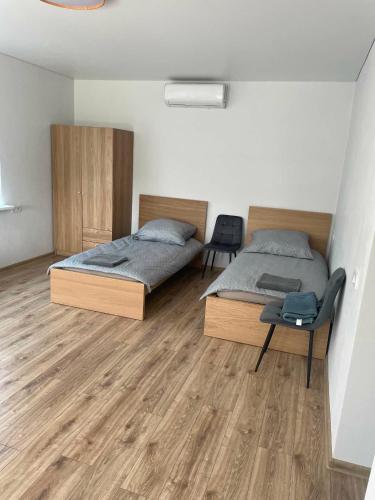 two beds in a room with wooden floors at Pušų Sodas in Birštonas