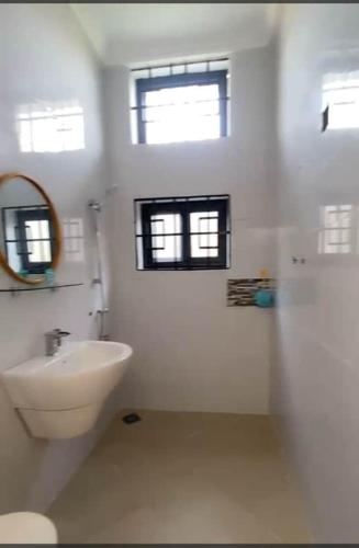 a white bathroom with a sink and a toilet at Mada's House F H L in Abomey-Calavi