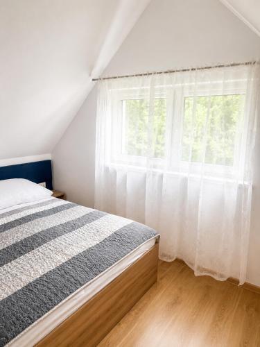 a bedroom with a bed and a window at Lubiatowe Love - domki w otulinie lasu in Lubiatowo