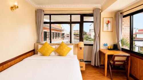 a bedroom with a bed and a desk and a window at Boudha Mandala Hotel in Kathmandu