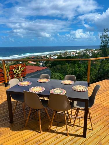 a black table and chairs on a deck with the ocean at La Villa Bleu Lagon in Petite Île
