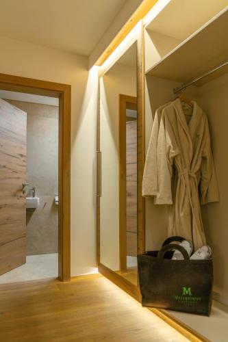 a bathroom with a walk in shower and a robe at Hotel Metzgerwirt in Sankt Veit im Pongau