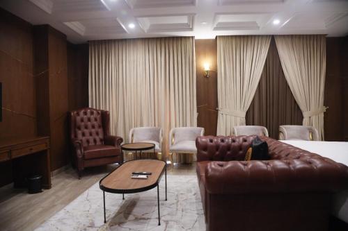 ein Hotelzimmer mit Sofa, Tisch und Stühlen in der Unterkunft Taj Signature Boutique Hotel Islamabad by LMY Hospitality in Islamabad