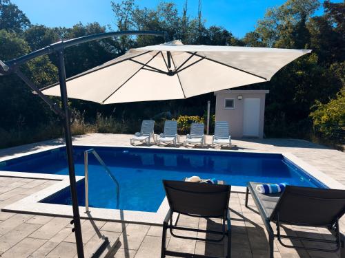 an umbrella and chairs next to a swimming pool at Holiday Home Slap Koćuša in Ljubuški